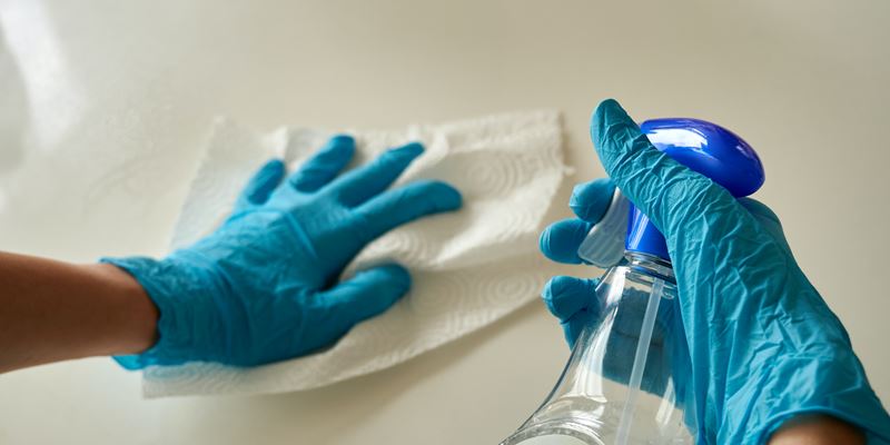 Person disinfecting surface with antibacterial spray 