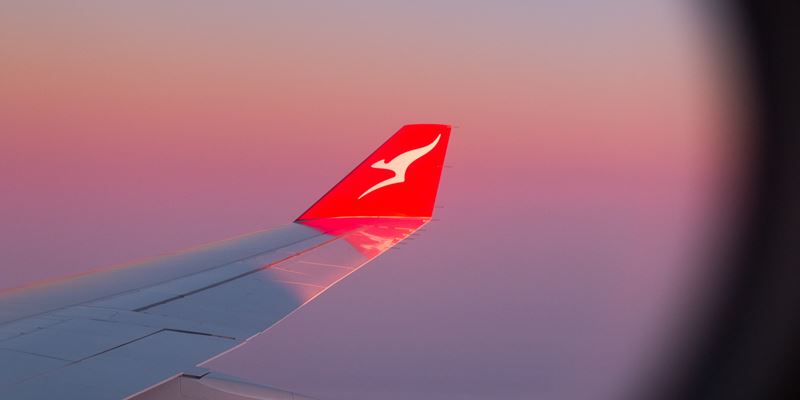 Qantas airline plane wing high in the sky at sunrise